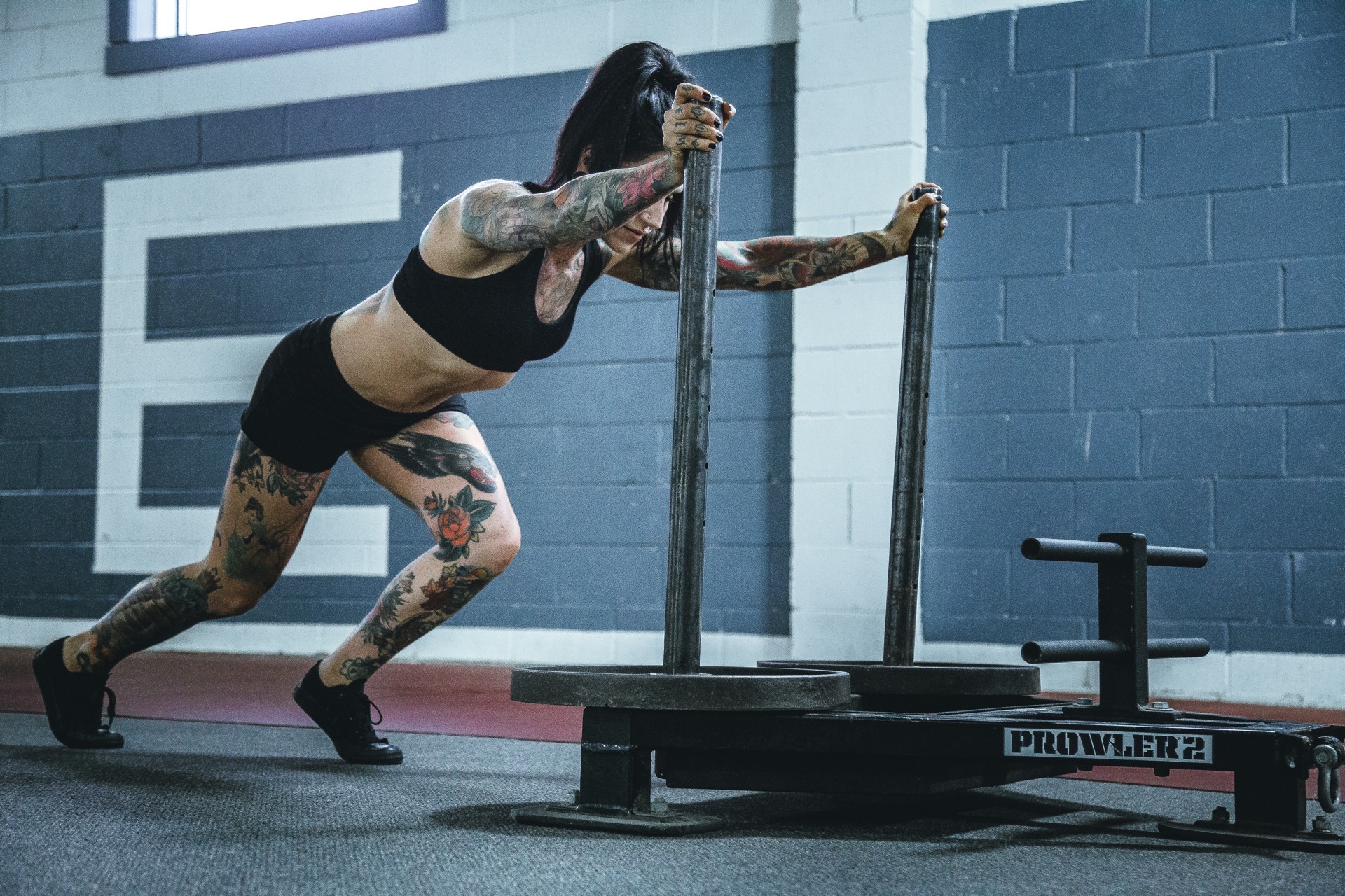 Athlete pushing a prowler sled in a gym